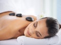 Calm, hot stone and woman with massage at spa for wellness, health and back treatment. Self care, cosmetic and young Royalty Free Stock Photo