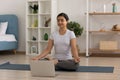 Calm Indian woman meditating, practicing yoga online at home
