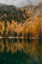 Calm lake and low flying clouds covering a rough mountain covered with colorful autumn foliage Royalty Free Stock Photo