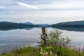 Calm lake with reflections of mountains and sky and a rescue ring in midst of colorful wildflowers in the foreground