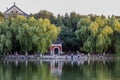 The calm lake reflects green trees and red arched doors