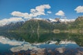 A calm lake by the road in Norway, the water surface is like a mirror, reflecting the blue sky and white clouds Royalty Free Stock Photo