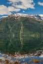 A calm lake by the road in Norway, the water surface is like a mirror, reflecting the blue sky and white clouds Royalty Free Stock Photo