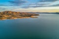 Calm lake and rolling yellow hills at sunset.