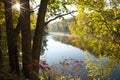 Calm lake and trees in autumn color with a sunburst in the morning Royalty Free Stock Photo