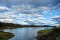 a calm lake with white clouds in the sky above it Royalty Free Stock Photo