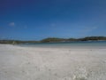 Calm landscape with an empty beach and a wonderful blue sky, a summer day and a calm sea with green vegetation, typical of a Royalty Free Stock Photo