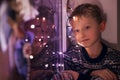 Calm little boy on the windoe with Christmas Lights