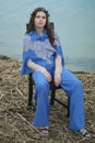 Calm lonely fashion model sitting on a chair in a cloudy day on a beach