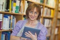 Calm mature librarian working with her tablet in library Royalty Free Stock Photo