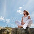 Calm mature woman relaxing in yoga position on a stone Royalty Free Stock Photo