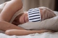 Calm mature woman wearing sleeping mask relaxing in bed