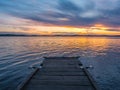 Calm and meditation concept. Sunset on the lake, wooden bridge in the foreground, quiet water, cloudless sky. Blue hour Royalty Free Stock Photo