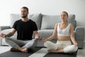 Calm young couple meditate in lotus position on floor mats