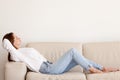 Calm millennial woman relaxing lying on sofa in modern apartment Royalty Free Stock Photo