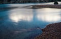 Calm shimmering mountain river with red pebbles