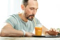 Calm occupied man drinking juice and using the tablet.