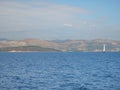 Calm ocean with glistening water and a coastal town and mountains with windmills in the horizon