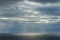 Calm Ocean Horizon With Sun Rays Breaking Through Dramatic Cloudy Sky Over Reflective Water Royalty Free Stock Photo