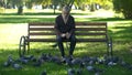 Calm old man sitting on bench in park and feeding pigeons, loneliness in old age