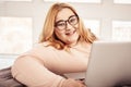 Contented ginger plus-size woman wearing clear glasses