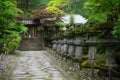 Calm and peaceful green Japanese garden with small stony statues, steps and temple as a symbol of harmony, balance and relaxation