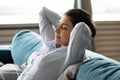 Calm peaceful Indian woman relaxing on cozy sofa at home