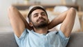 Calm peaceful man relaxing with closed eyes leaning back on sofa