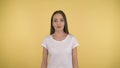 Calm peaceful woman on yellow background in studio isolated. Middleweight woman in basic white t-shirt