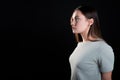 A calm portrait of a young brunette in profile, looking forward. Contour light, copy the space on the left,