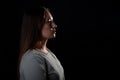 A calm portrait of a young brunette in profile, looking forward. Contour light, copy the space on the right,