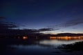 Calm reflective fjord surface at night time with city lights