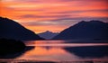 Calm reflective lake with shoreline mountains under the scenic sunset sky