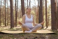 Calm relaxed pregnant woman doing yoga in nature outdoors sitting on mat in lotus pose enjoying meditation outdoors wearing light Royalty Free Stock Photo