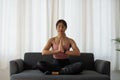 Calm relaxed young asian woman sitting in lotus position with hands up namaste gesture, closed eyes, breathing, resting Royalty Free Stock Photo