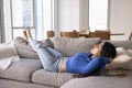 Calm relaxed young Indian woman resting on soft comfortable couch Royalty Free Stock Photo