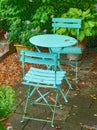 A calm and relaxing garden with antique table and chairs. Handcrafted metal furniture on a patio or veranda during