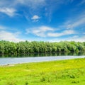 Calm river and green hills with blooming wild flowers and trees at sunny summer day Royalty Free Stock Photo