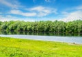 Calm river and green hills with blooming wild flowers and trees at sunny summer day Royalty Free Stock Photo
