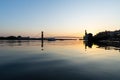 calm river waters reflecting vibrant sunset behind distant bridge Royalty Free Stock Photo
