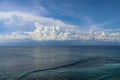 Calm sea and blue sky from the side of a boat with bow wave wake and cumulonimbus clouds on the horizon. Royalty Free Stock Photo