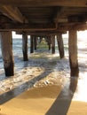 Calm sea waves under a wooden plank jetty in Seaford, VIC, Australia