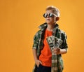 Calm self-confident rich teenager boy in round sunglasses, checkered plaid shirt and jeans stands holding fan of cash