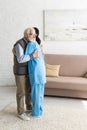 Calm senior man hugging with nurse, standing