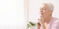 Calm senior woman meditating, listening to classical music