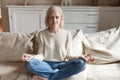 Calm senior woman practicing yoga meditating on couch Royalty Free Stock Photo