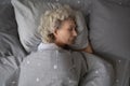 Calm senior woman sleeping in comfortable home bed