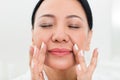 Calm senior woman using cosmetic at spa Royalty Free Stock Photo