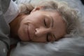 Calm serene old 60s lady enjoying good healthy sleep