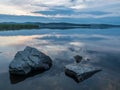 Calm, serenity, meditation concept. Sunset on the lake, stones in the water in the foreground, quiet water, cloudless sky